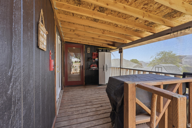 2500 North Fort Lane, Unit 220 Layton, UT 84041 - Photo 21 of 23 Covered outdoor deck with exposed wood beam ceiling, wood-plank flooring, and dark board-and-batten style siding