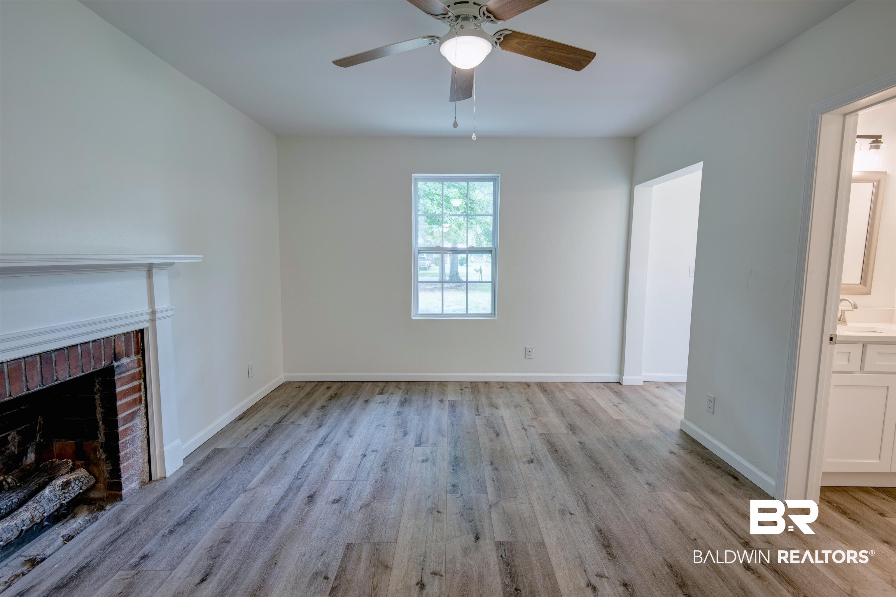 510 East Myrtle Avenue Foley, AL 36535 - Photo 5 of 22 Unfurnished living room with light wood finished floors, ceiling fan, and a brick fireplace