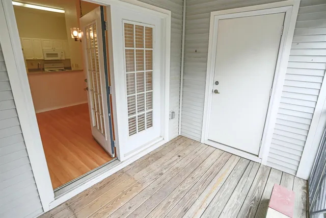 a view of a hallway with wooden floor and a bathroom