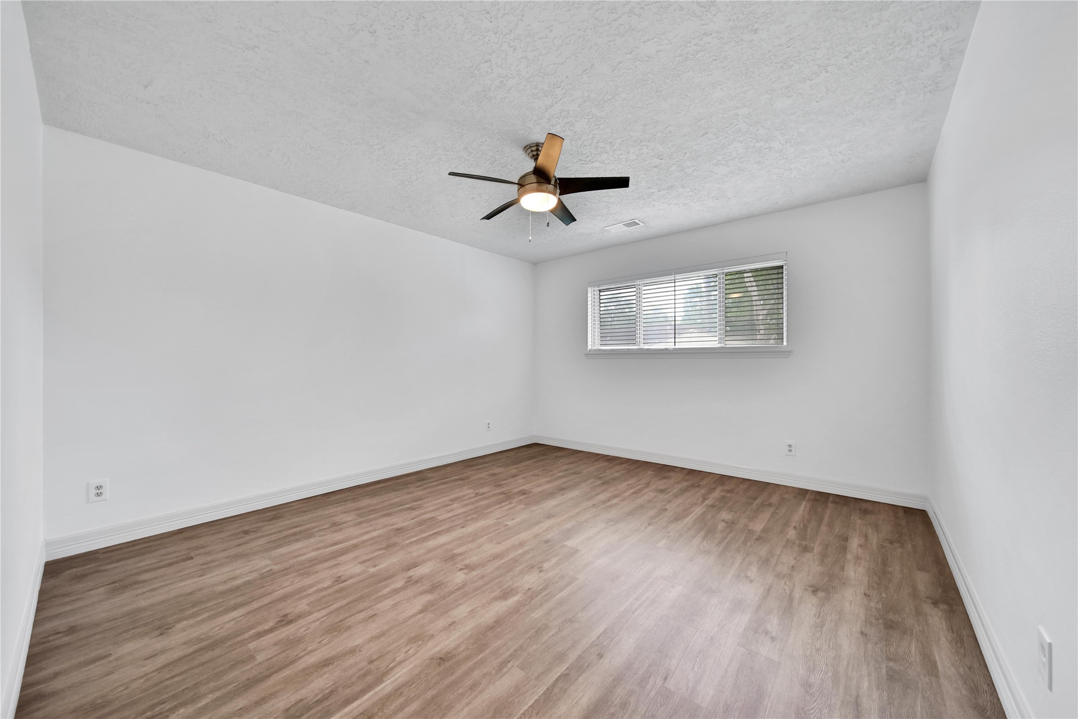 9411 Roos Road Houston, TX 77036 - Photo 23 of 41 an empty room with wooden floor ceiling fan and windows