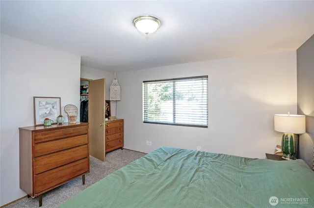 a bedroom with a bed and a lamp on dresser