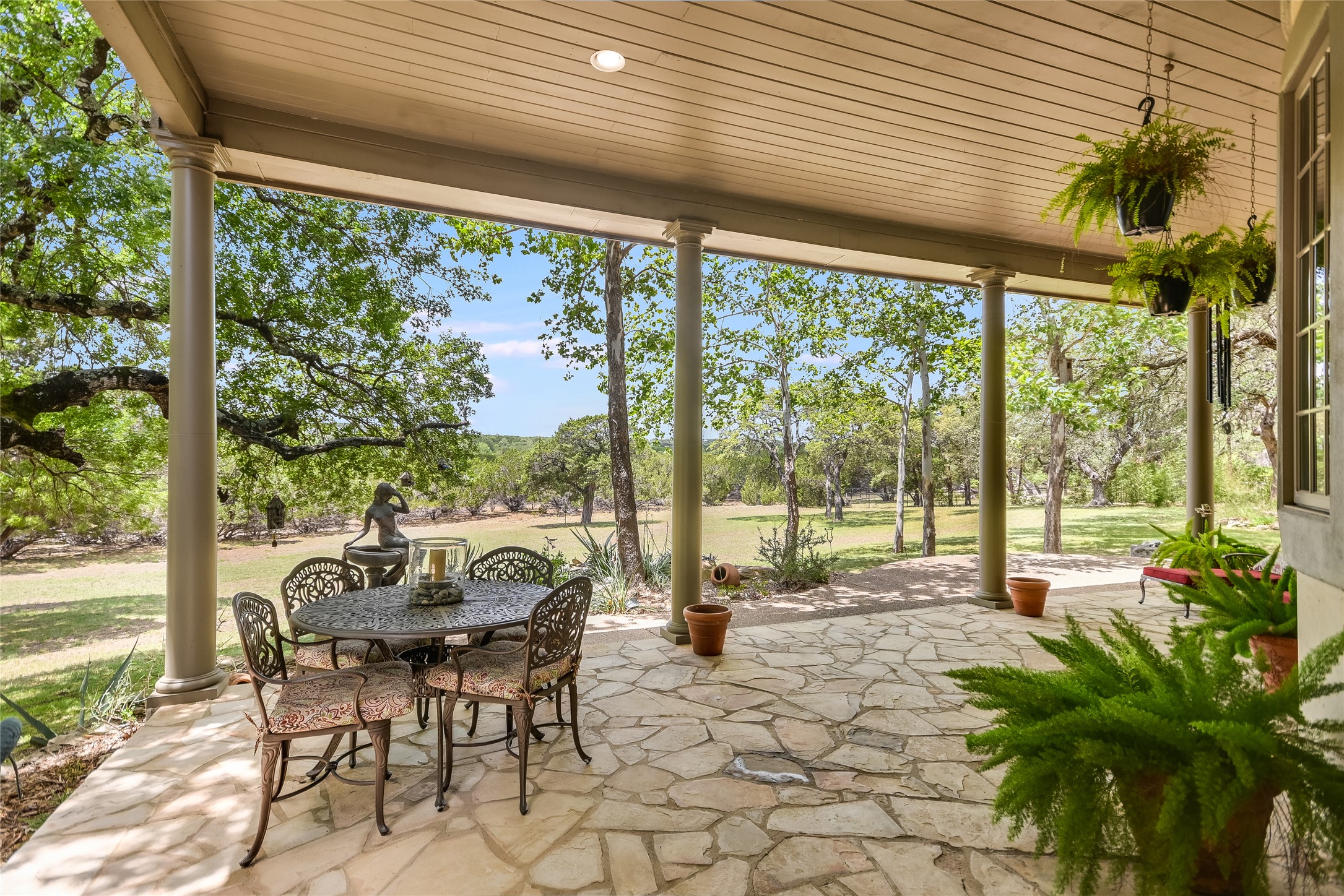 8611 Young Lane Austin, TX 78737 - Photo 28 of 40 a view of a patio with table and chairs potted plants and floor to ceiling window