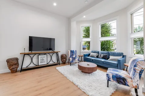 a living room with furniture a flat screen tv and a large window