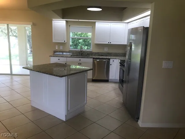 a kitchen with stainless steel appliances granite countertop a sink and a refrigerator