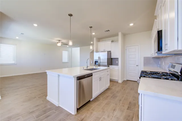 a view of kitchen with kitchen island wooden floor center island and stainless steel appliances