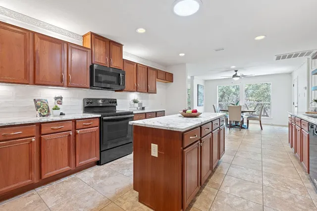 a kitchen with kitchen island granite countertop a sink counter top space appliances and a window