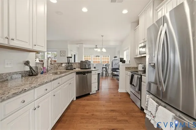 a kitchen with stainless steel appliances white cabinets and a stove a refrigerator with a sink