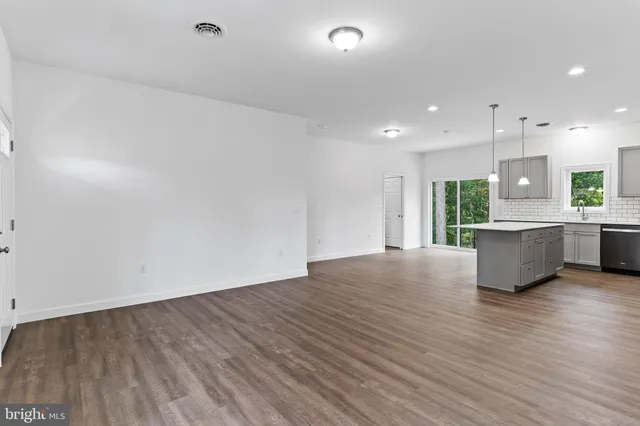 a view of a hallway with wooden floor and a bathroom