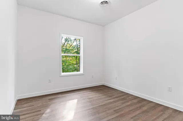 an empty room with wooden floor and window