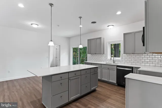 a kitchen with stainless steel appliances granite countertop a sink a stove and a wooden floors