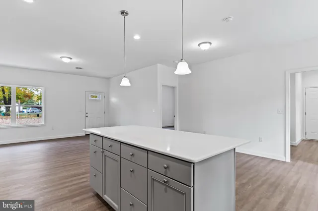 a room with a chandelier fan and wooden floor