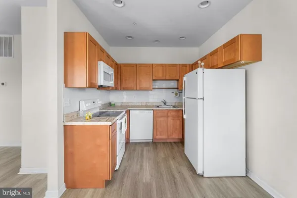 a kitchen with stainless steel appliances granite countertop a refrigerator a sink dishwasher a stove with wooden floor