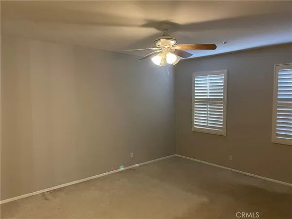 a view of a livingroom with a chandelier fan and windows
