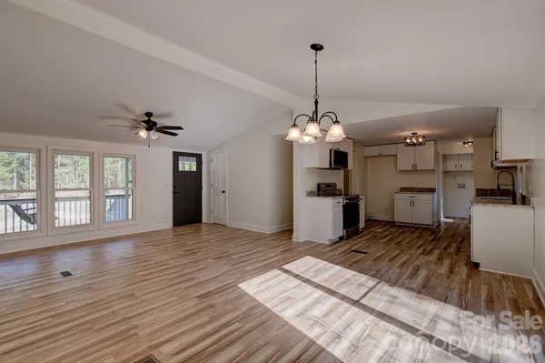 a view of a room with wooden floor a ceiling fan and kitchen space