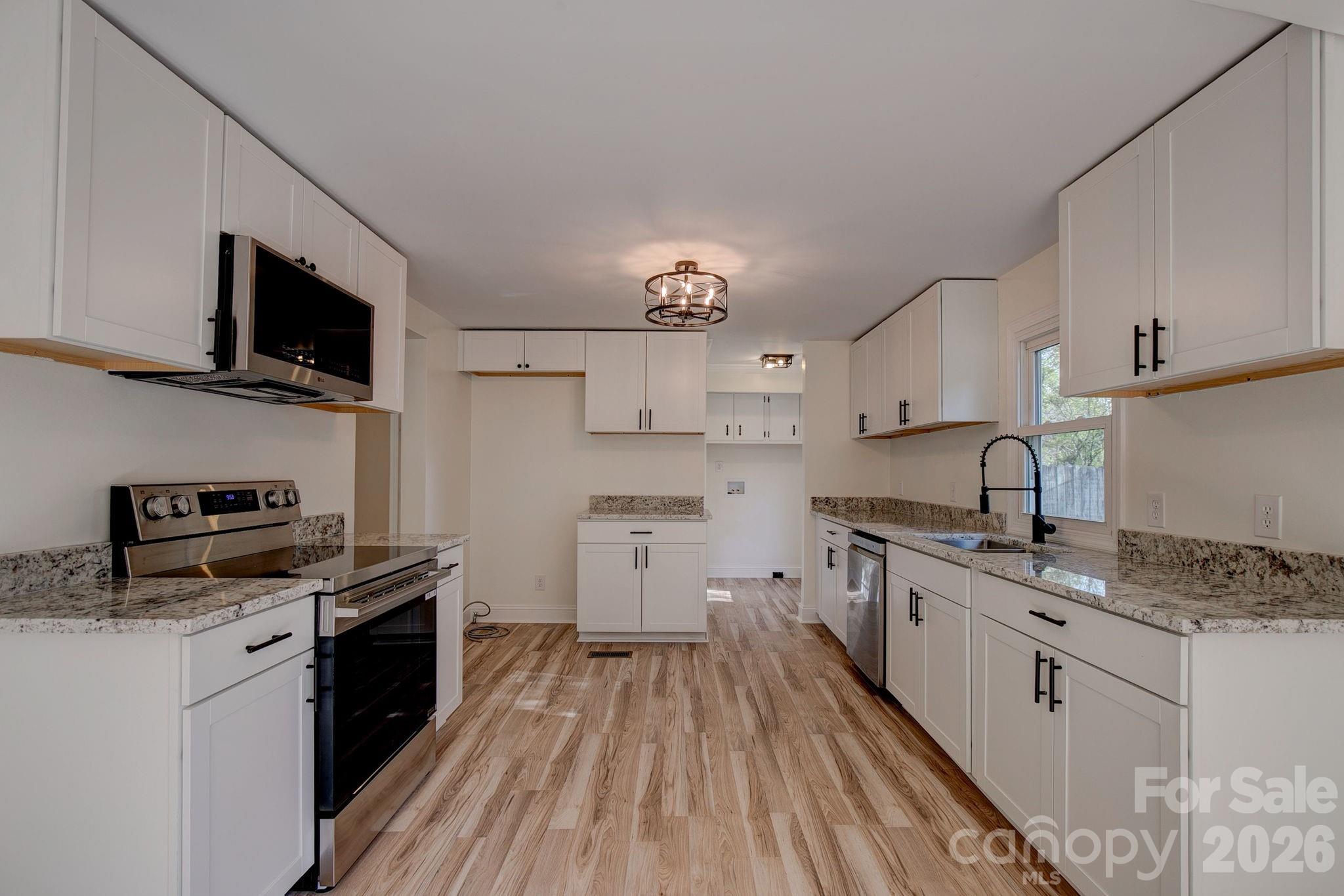 4282 Fred Gardner Road Kershaw, SC 29067 - Photo 13 of 36 a kitchen with stainless steel appliances granite countertop a sink stove oven a refrigerator with white cabinets and wooden floor