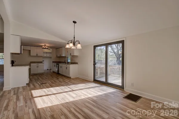 a view of a room with wooden floor kitchen view and a window