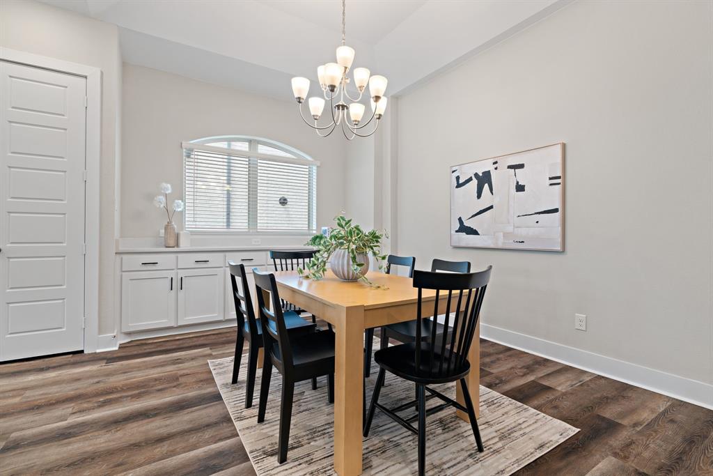 1821 Stonewall Road Argyle, TX 76226 - Photo 13 of 40 Dining area featuring wood-finish flooring, a contemporary chandelier, and a built-in white cabinet system with a light-colored countertop