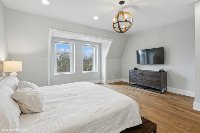 a bedroom with a bed a dresser and flat screen tv