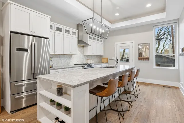 a kitchen with stainless steel appliances granite countertop a refrigerator a sink dishwasher a stove and a refrigerator with wooden floor