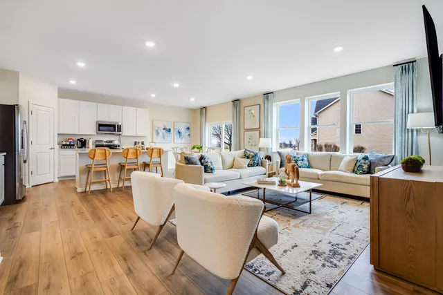 a living room with furniture and kitchen view with wooden floor