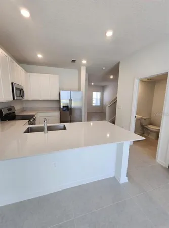 a large kitchen with kitchen island a white counter space and a sink