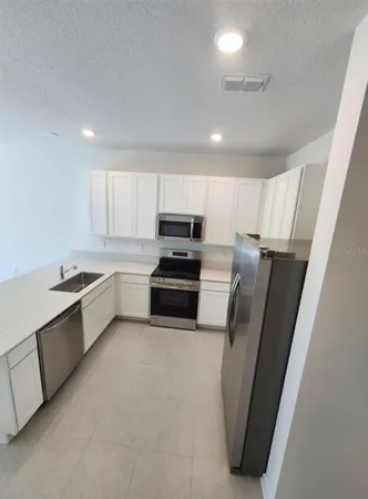 a kitchen with stainless steel appliances a refrigerator a sink a stove a microwave and cabinets