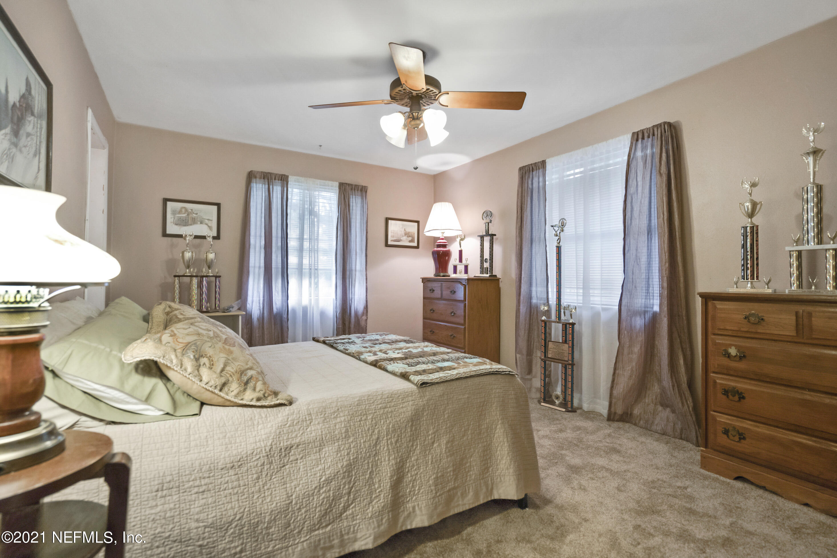 4004 Rogero Road Jacksonville, FL 32277 - Photo 11 of 19 a spacious bedroom with a bed and a chandelier
