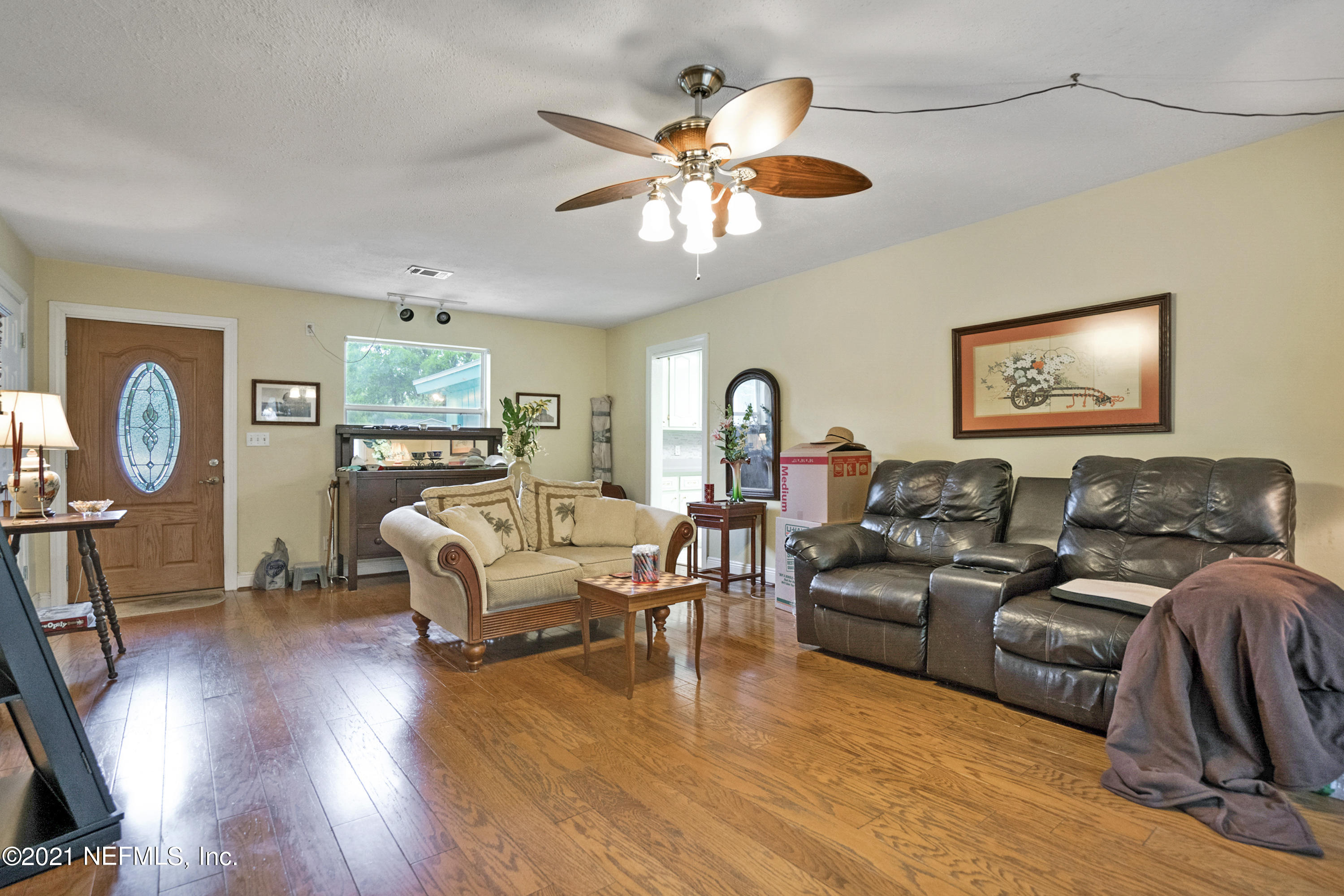 4004 Rogero Road Jacksonville, FL 32277 - Photo 4 of 19 a living room with furniture a chandelier and a flat screen tv