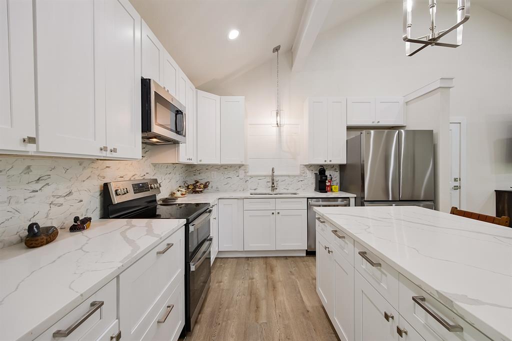 114 Ricky Road Gun Barrel City, TX 75156 - Photo 10 of 18 Modern kitchen featuring white cabinetry, stainless steel appliances, light-toned countertops with veining, a matching backsplash, and wood-finish flooring