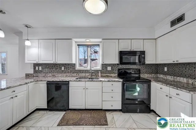 a kitchen with stainless steel appliances kitchen island granite countertop a refrigerator a stove a sink and a oven with white cabinets