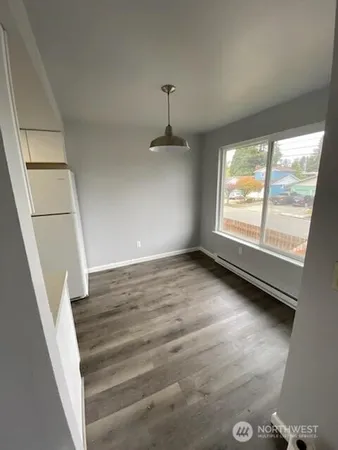 a view of an empty room with wooden floor and windows