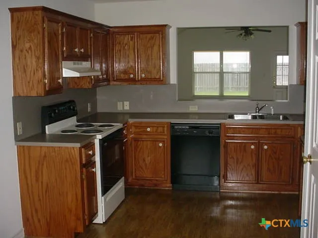 a kitchen with granite countertop a sink stove and cabinets