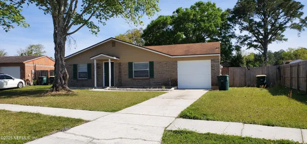 a front view of a house with a garden and tree