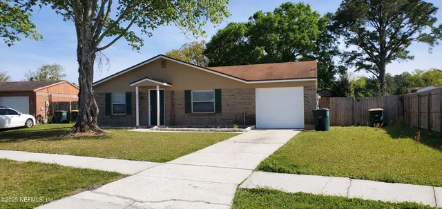 a front view of a house with a garden and tree