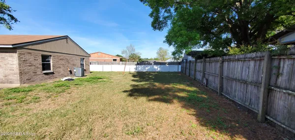 a view of a house with a small yard and wooden fence