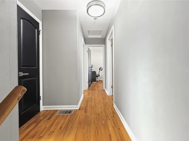 a view of a hallway with wooden floor and staircase