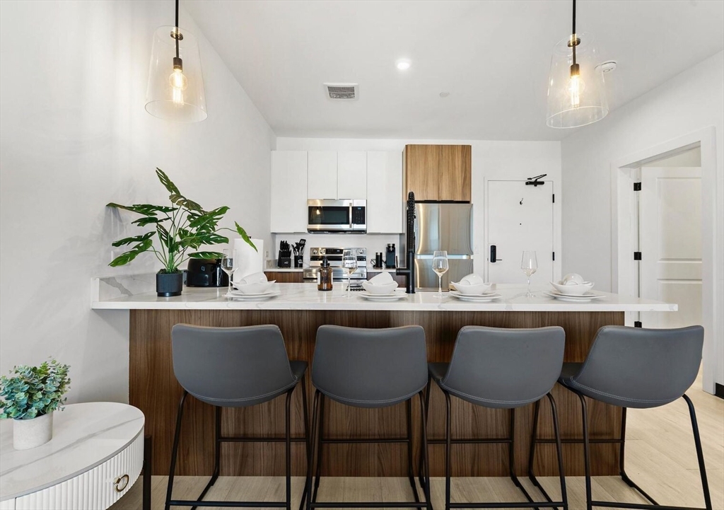600 Broadway, Unit 513 Chelsea, MA 02150 - Photo 2 of 31 a kitchen with a dining table chairs sink and cabinets