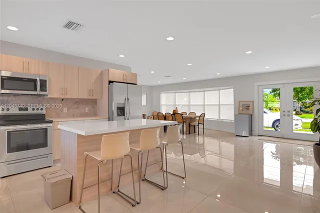 a kitchen with stainless steel appliances kitchen island granite countertop a stove a sink a dining table and chairs