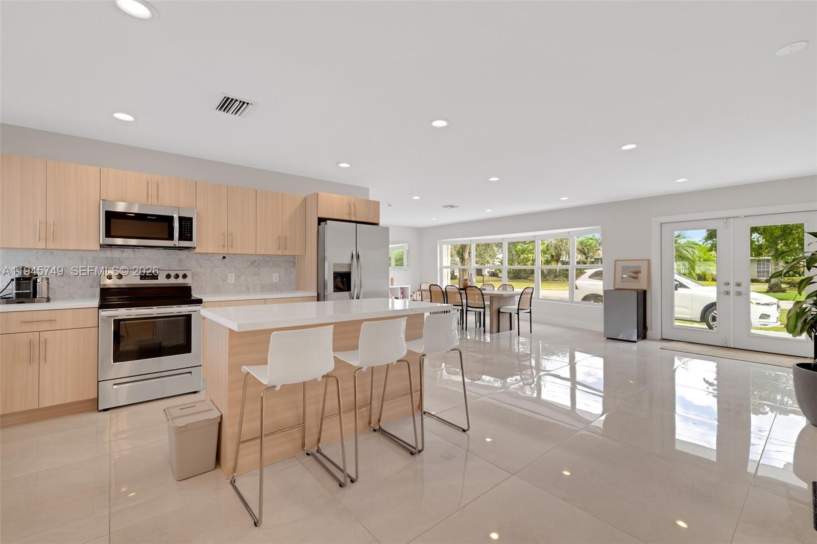3500 North Park Road Hollywood, FL 33021 - Photo 13 of 39 a kitchen with stainless steel appliances kitchen island granite countertop a stove a sink a dining table and chairs with wooden floor