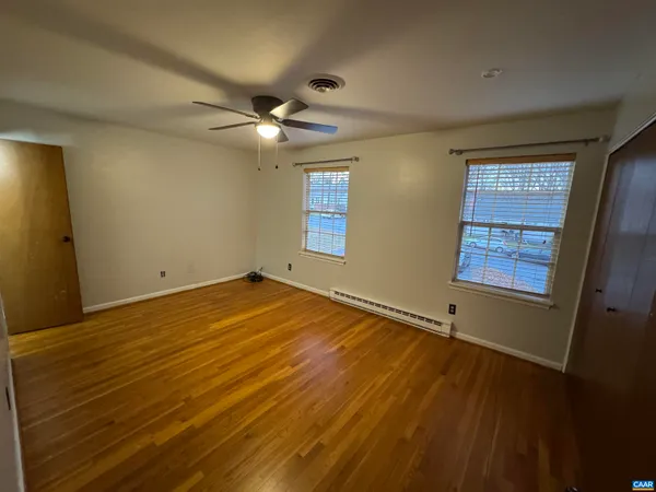 a view of empty room with wooden floor and fan