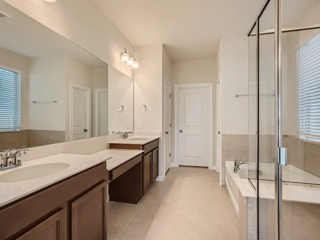 a spacious bathroom with a sink double vanity granite tub shower and mirror