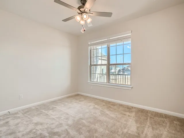 an empty room with a chandelier fan and windows