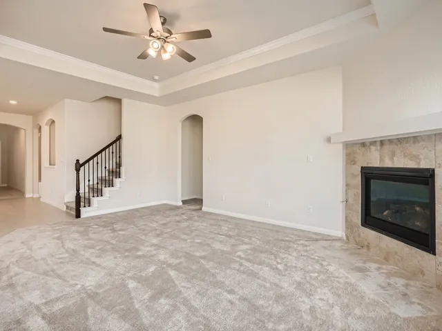 a view of an empty room with chandelier fan and fire place