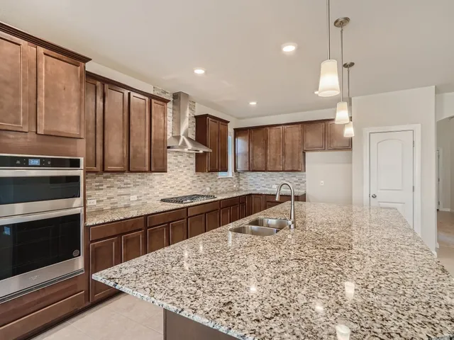 a large kitchen with kitchen island granite countertop a stove and a sink