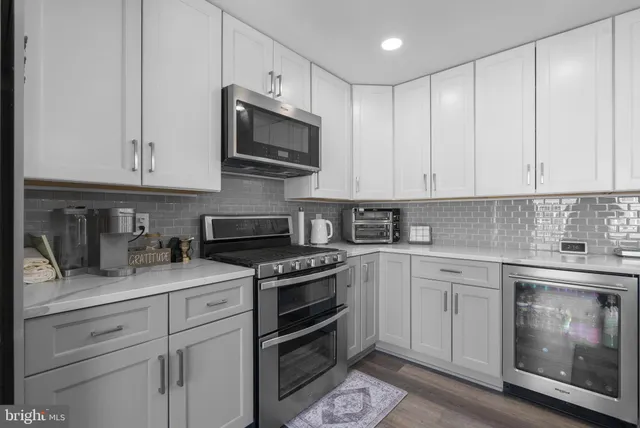 a kitchen with granite countertop white cabinets and stainless steel appliances