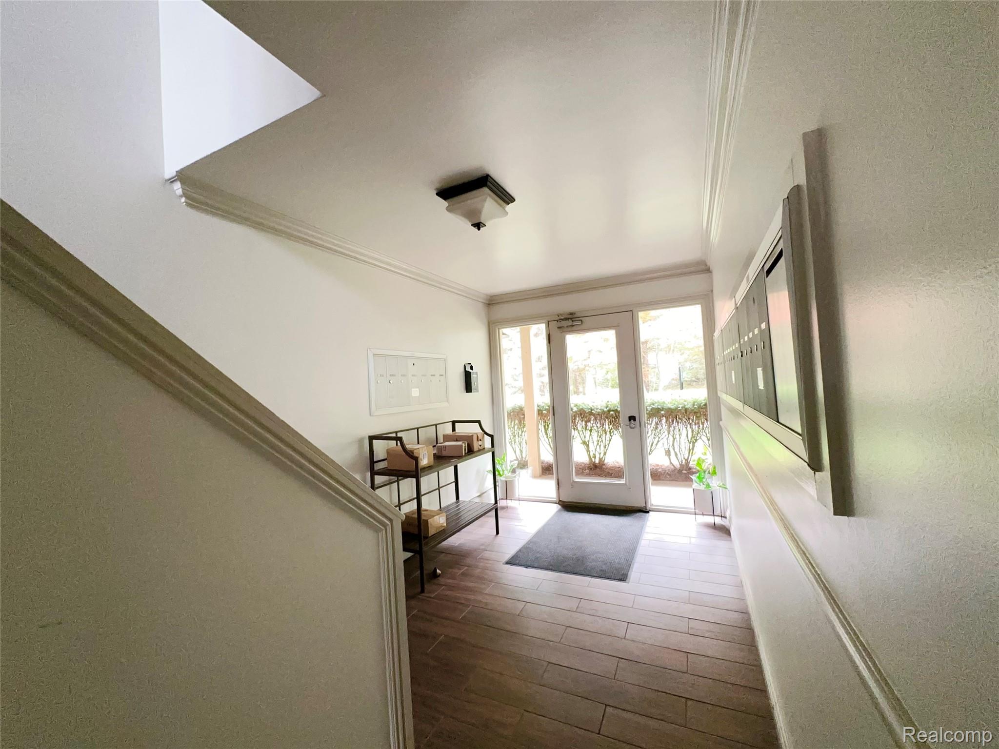 475 South Adams Road, Unit 8 Birmingham, MI 48009 - Photo 14 of 15 Wood-finish flooring, crown molding, modern ceiling fixture, glass-paned door, and built-in mailboxes