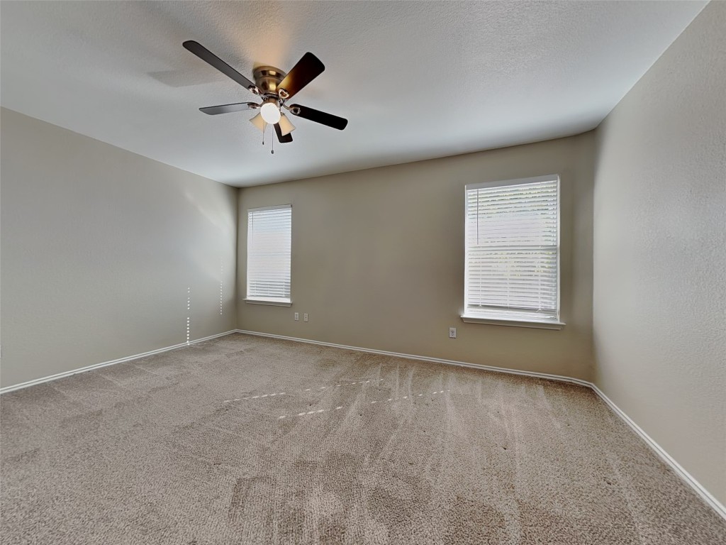 228 Fall Creek Drive Kyle, TX 78640 - Photo 7 of 19 Empty room featuring carpet, ceiling fan, and a textured ceiling