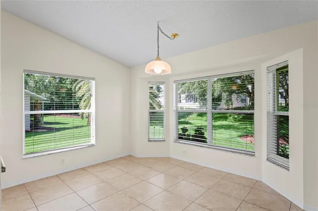 a view of an empty room with window and chandelier fan