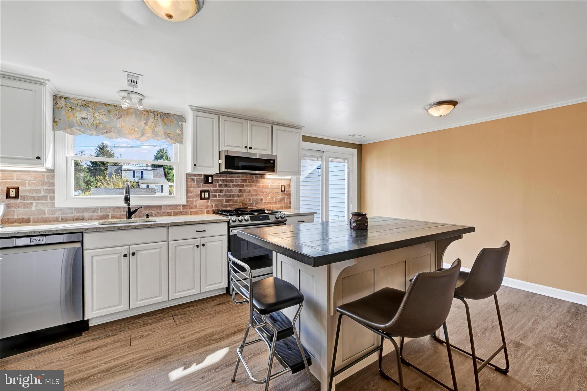 9 Othoridge Road Lutherville-Timonium, MD 21093 - Photo 6 of 37 a kitchen with stainless steel appliances a kitchen island hardwood floor sink stove dining table and chairs