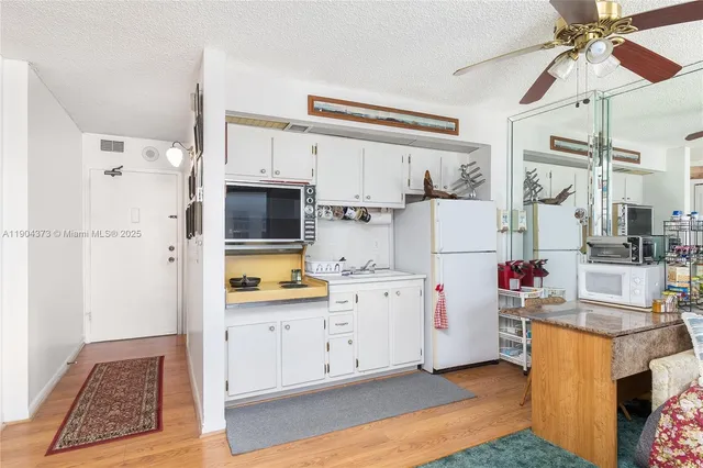 a very nice looking open kitchen with stainless steel appliances granite countertop a refrigerator and a stove top oven